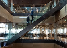 Two persons who are blurry because they are moving up a stair in a modern office environment
