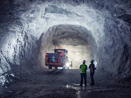 Two men standing in an underground mine looking at an underground drill rig